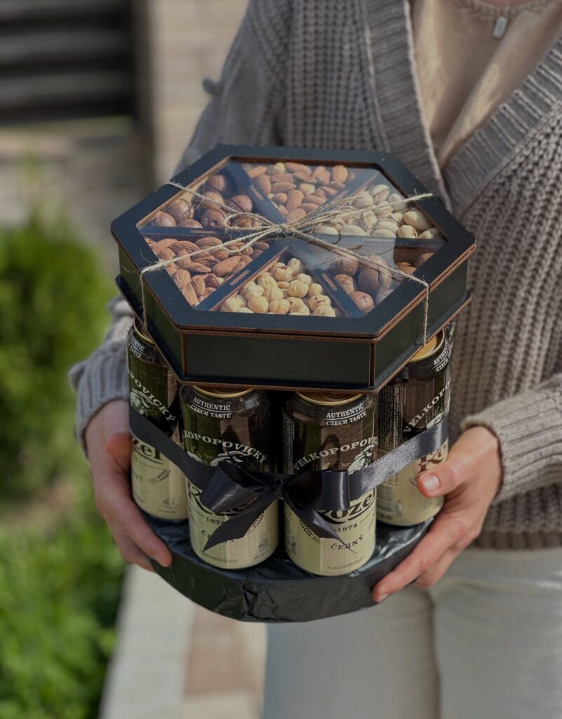 Hexagonal black gift basket with beer cans and assorted nuts held by a person