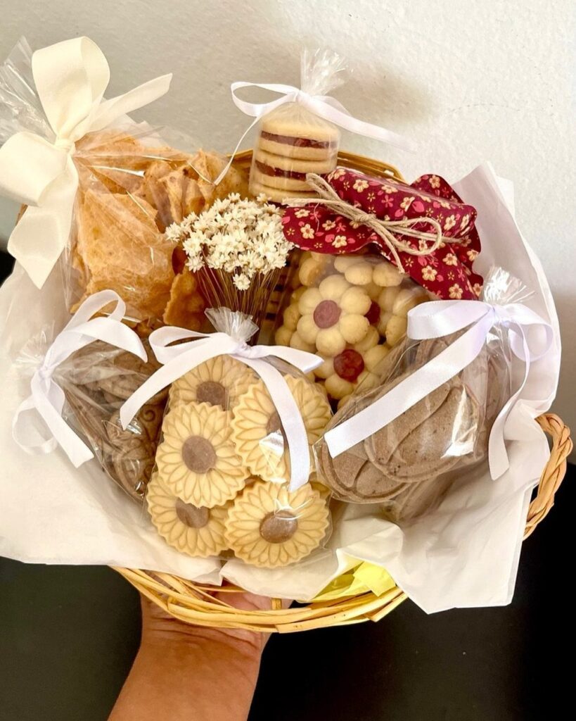 Wicker gift basket filled with assorted cookies in clear bags tied with ribbons.