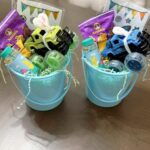 Two blue buckets filled with toy trucks, snacks, and water bottles for Easter.