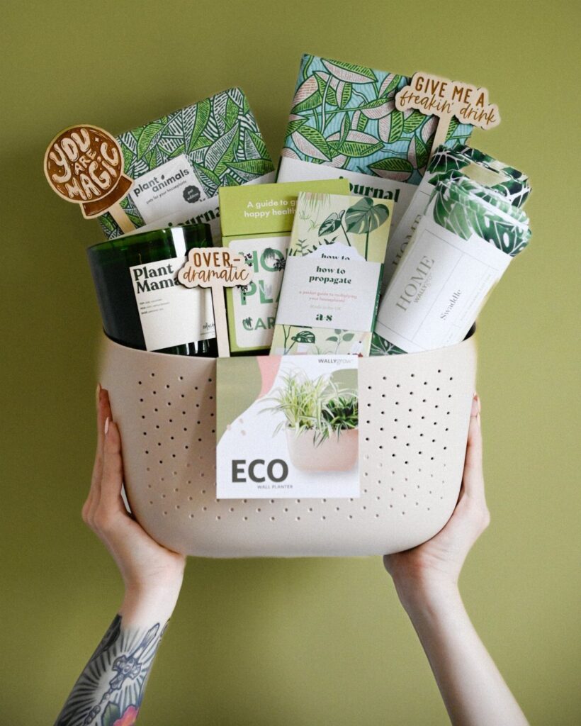 Beige perforated basket filled with plant-themed books, notebooks, and a green candle.