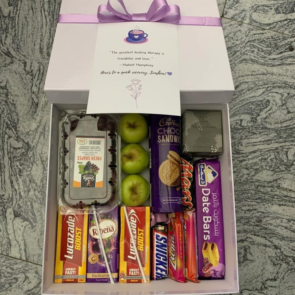 Gift box filled with fruit, energy drinks, cookies, and assorted sweet treats.