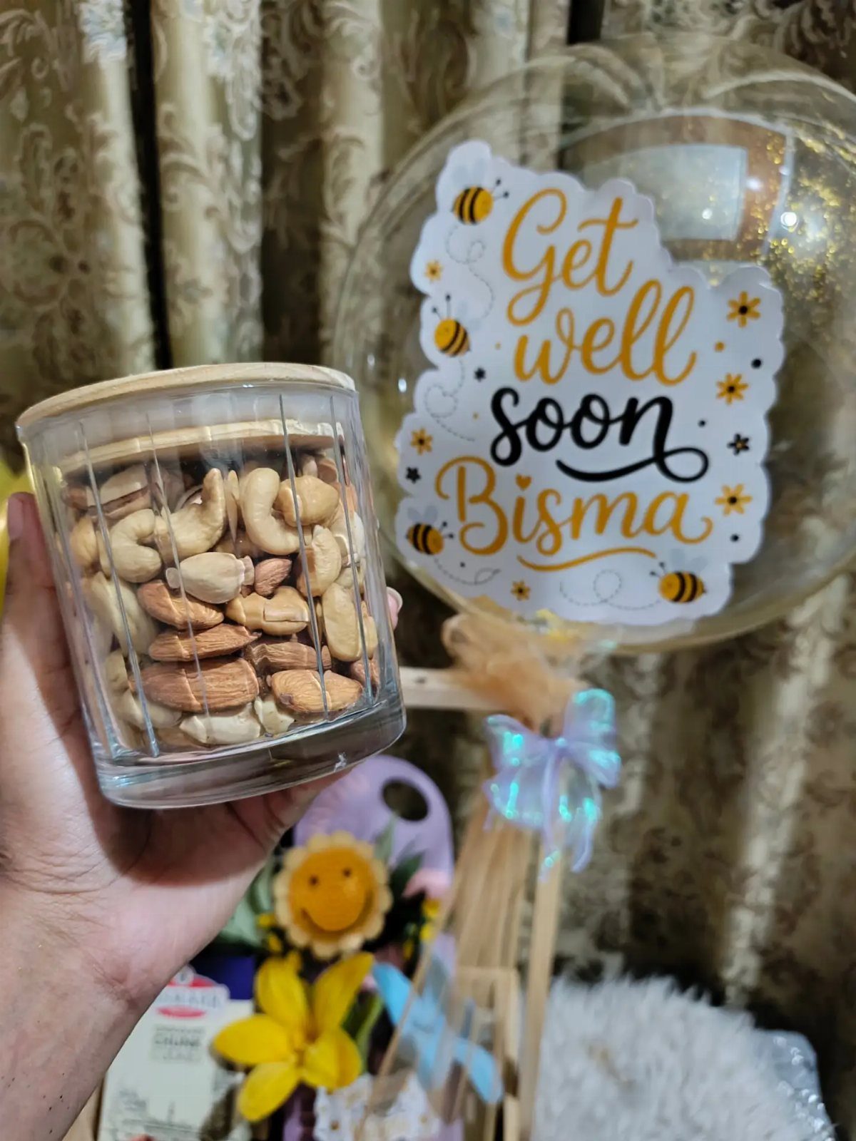 Glass jar of mixed nuts held in front of a get well balloon