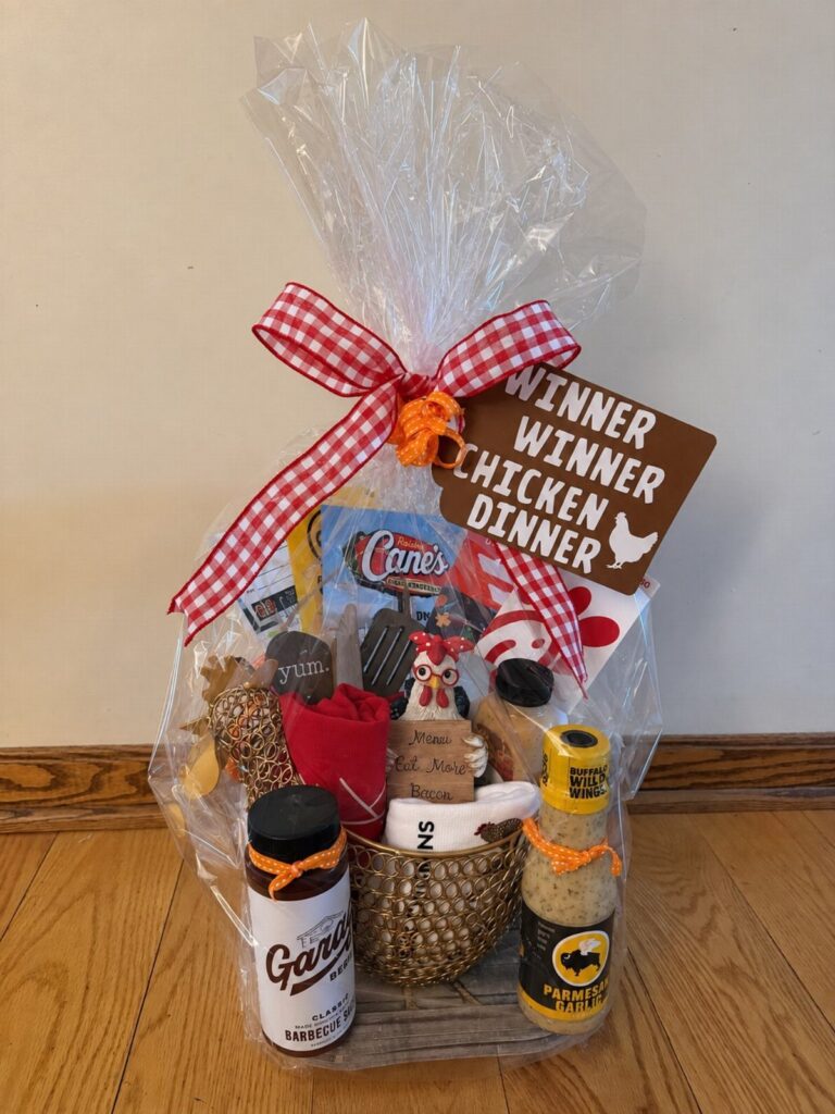 Gift basket wrapped in cellophane with a chicken dinner themed raffle sign.