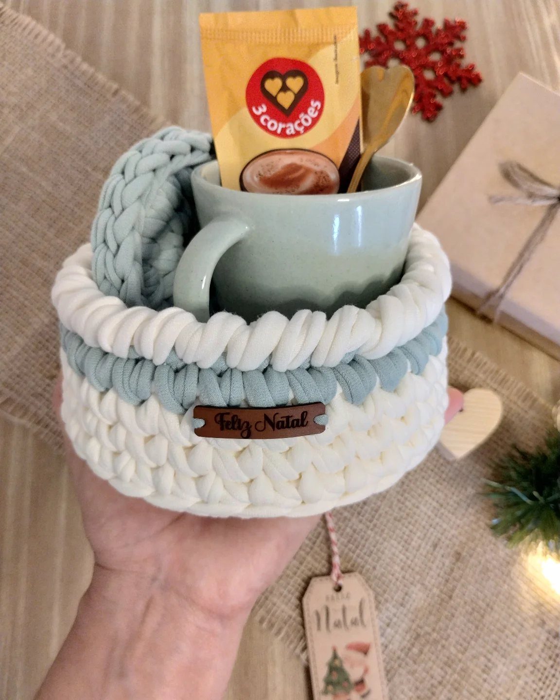 Crocheted white and blue basket containing a green mug with coffee sachet.