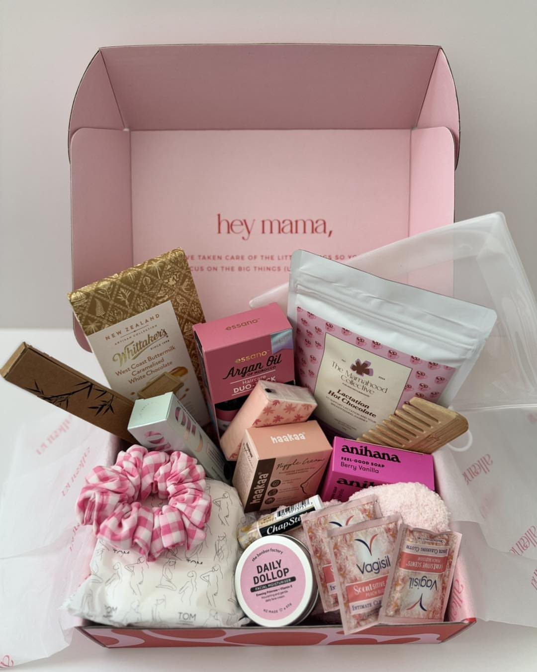 Pink gift box filled with chocolates, skincare, and a pink checkered scrunchie.