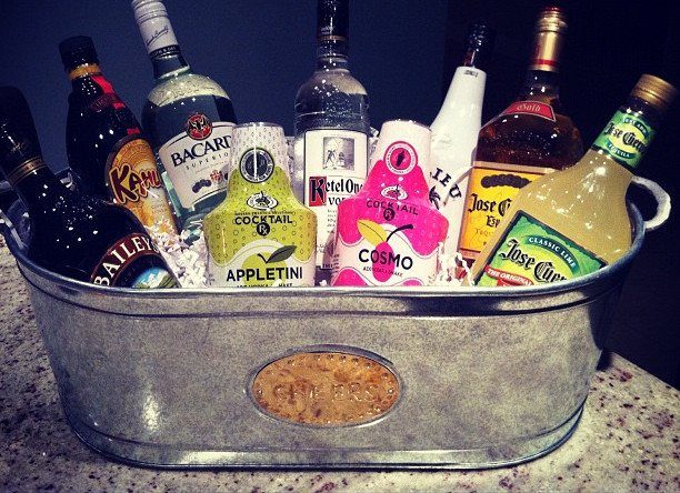 Assorted liquor and cocktail bottles arranged in a galvanized metal tub on granite.