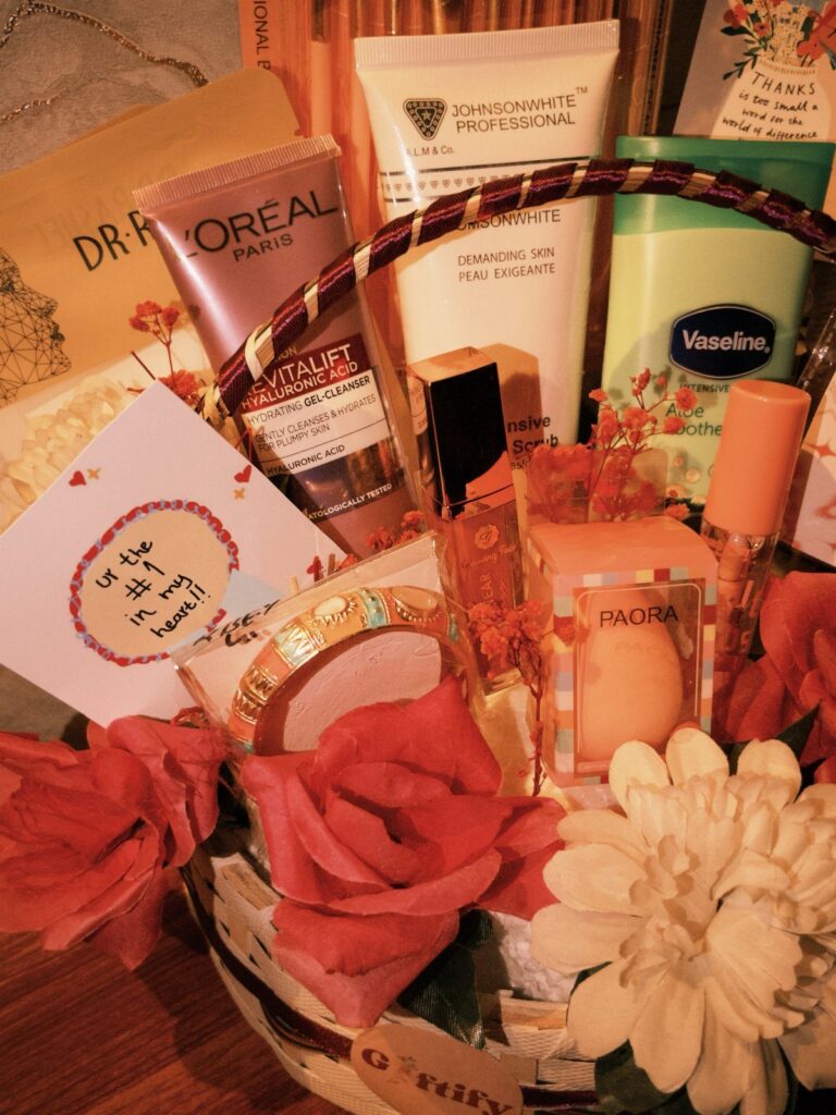 Gift basket with skincare products, artificial roses, and a heartfelt handwritten card.
