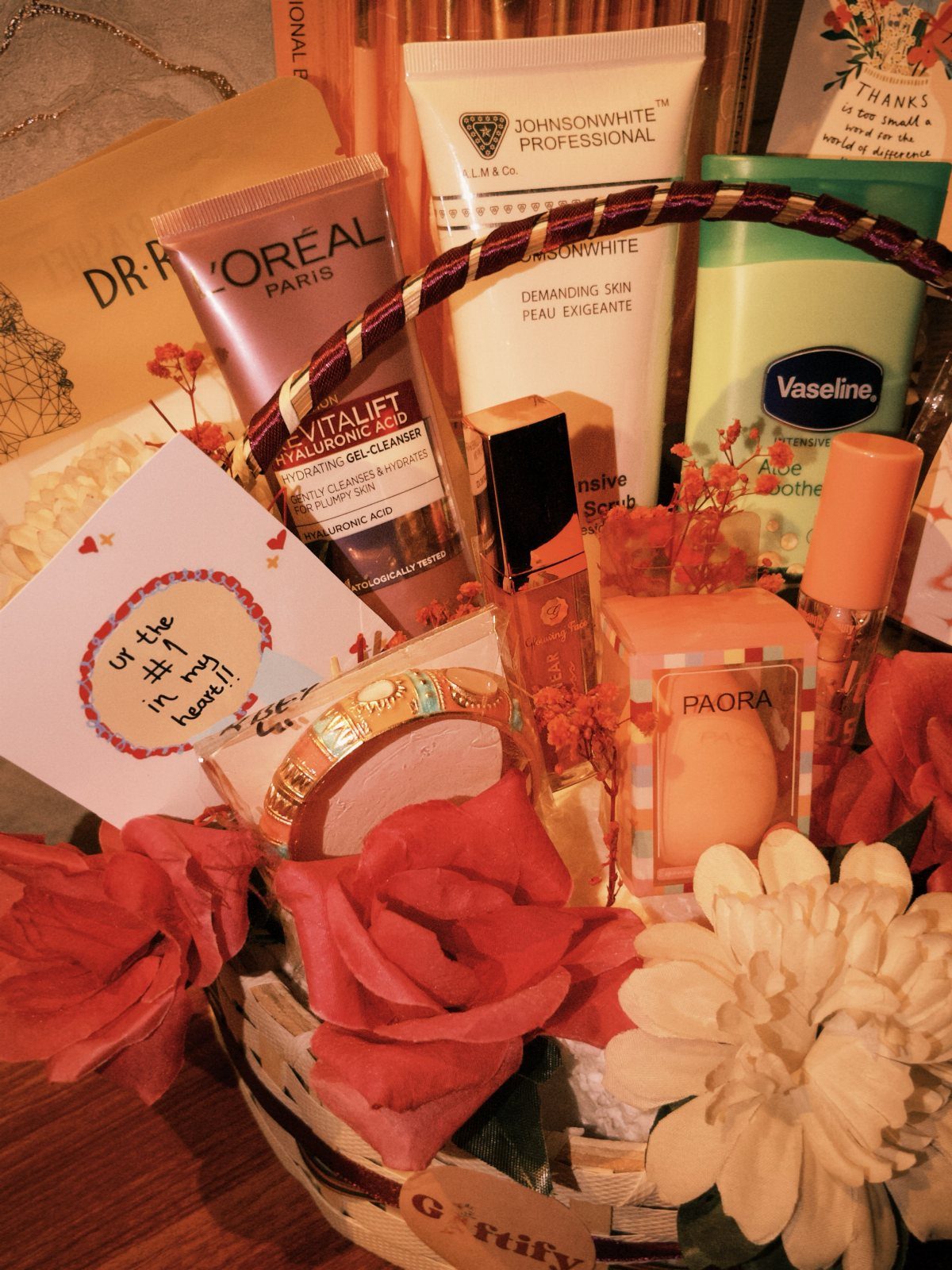 Gift basket with skincare products, artificial roses, and a heartfelt handwritten card.