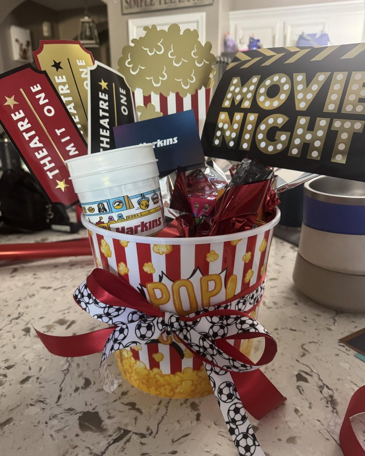 Movie night raffle basket in a popcorn bucket with snacks and movie tickets.