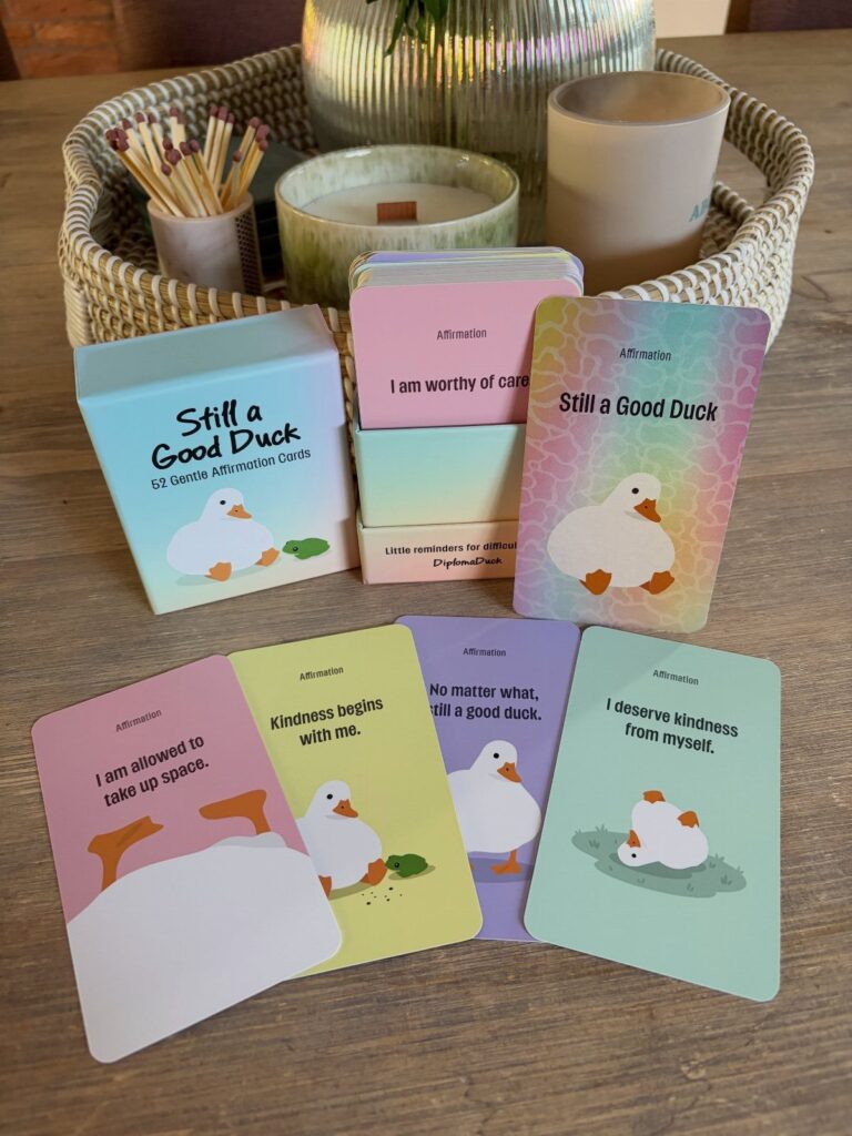 Affirmation cards with cute ducks and positive messages on a wooden table.