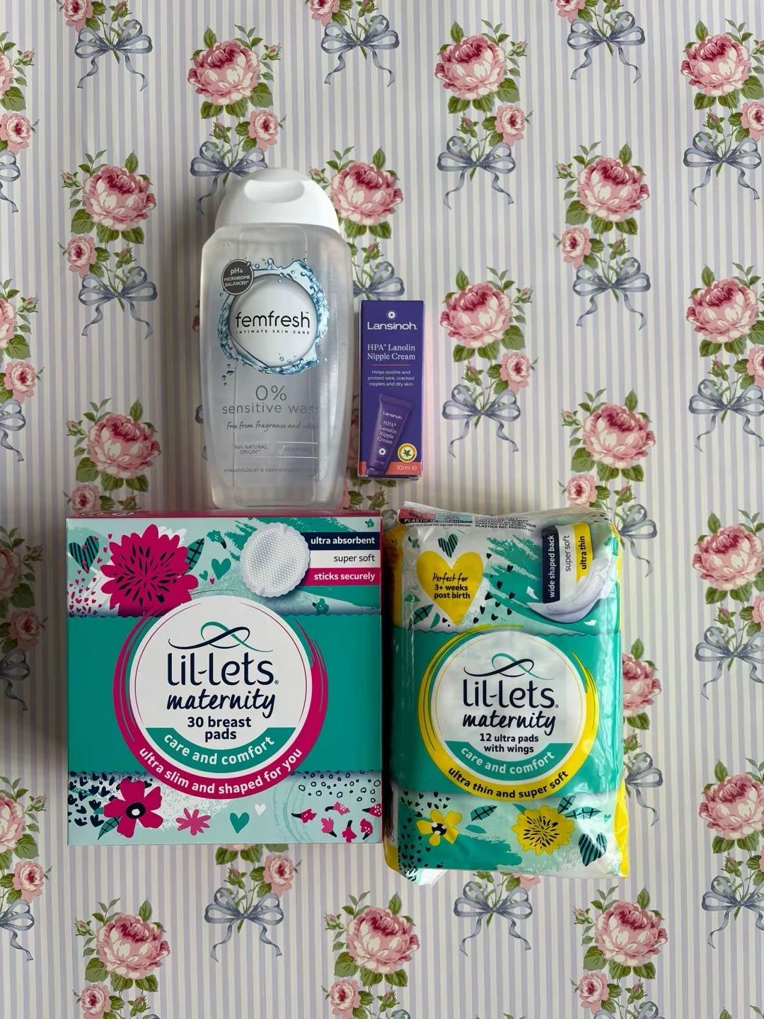 Postpartum care products including breast pads and wipes on floral wallpaper background
