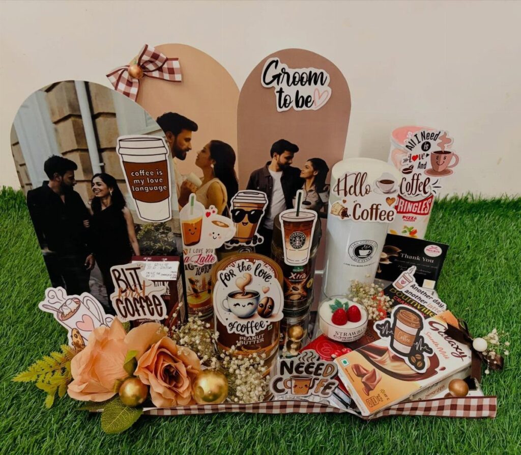 Coffee gift basket with coffee cups, couple photos, and peach roses on grass.