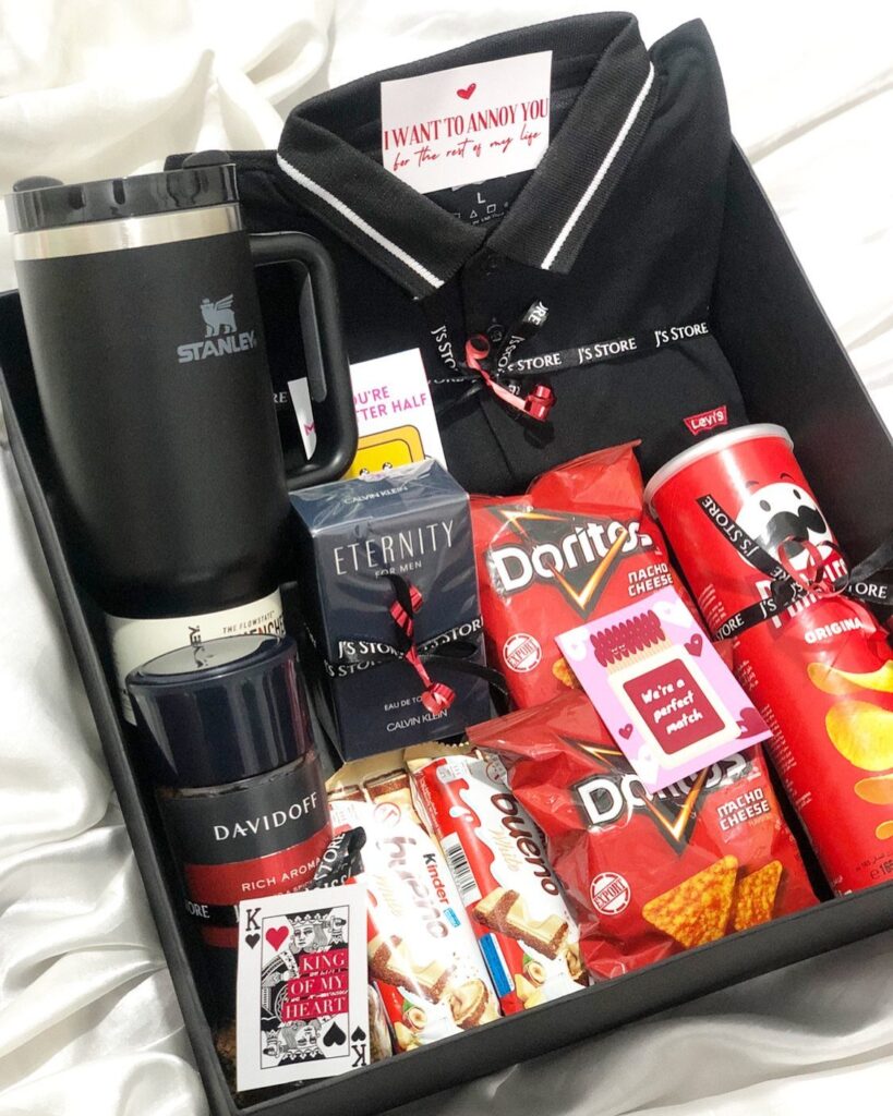 Gift basket for him with black polo shirt, Stanley tumbler, cologne, and snacks.
